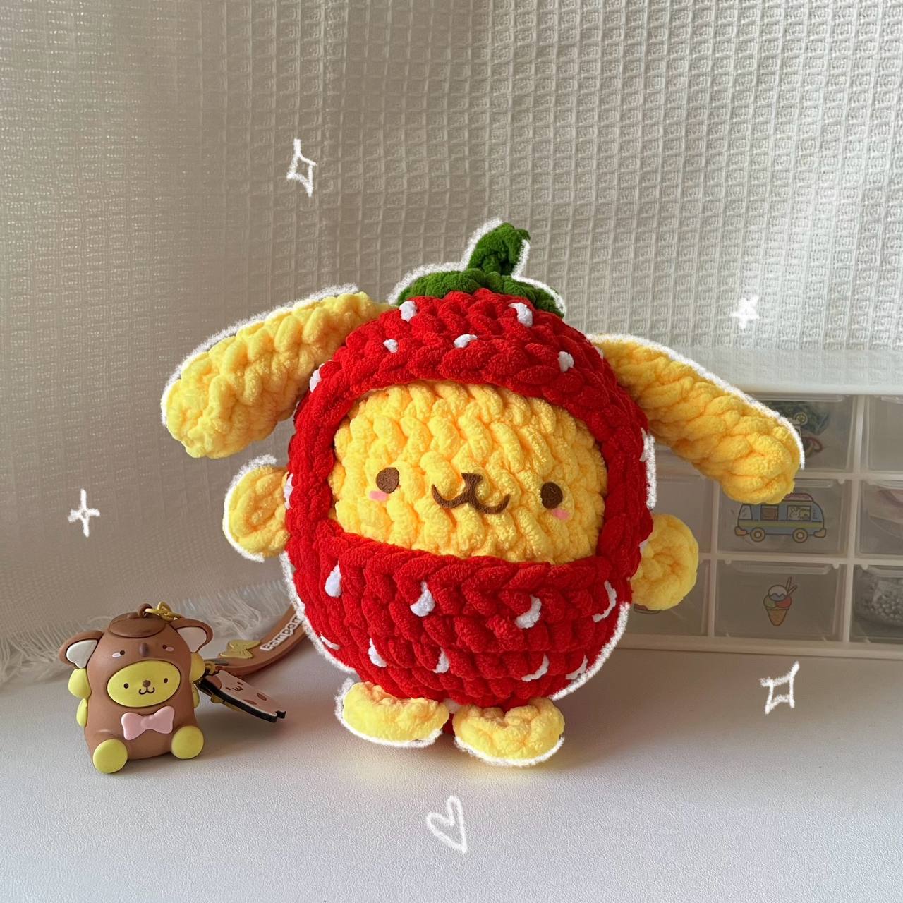 crochet version of Pompompurin character in a strawberry outfit